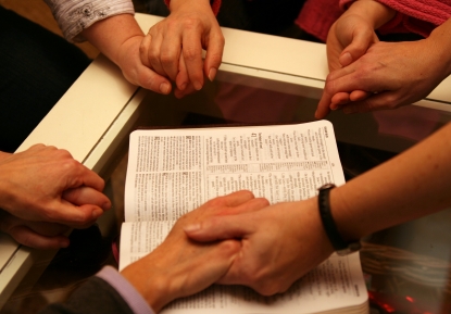 Family crossing arms over bible